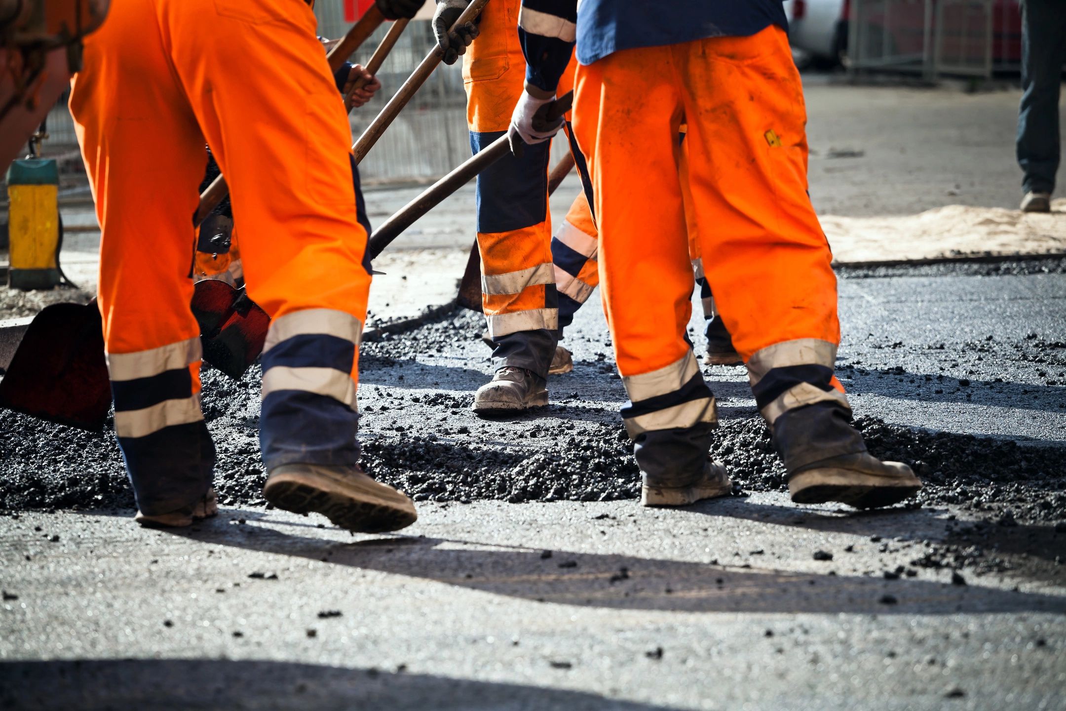 Construction workers spread asphalt,