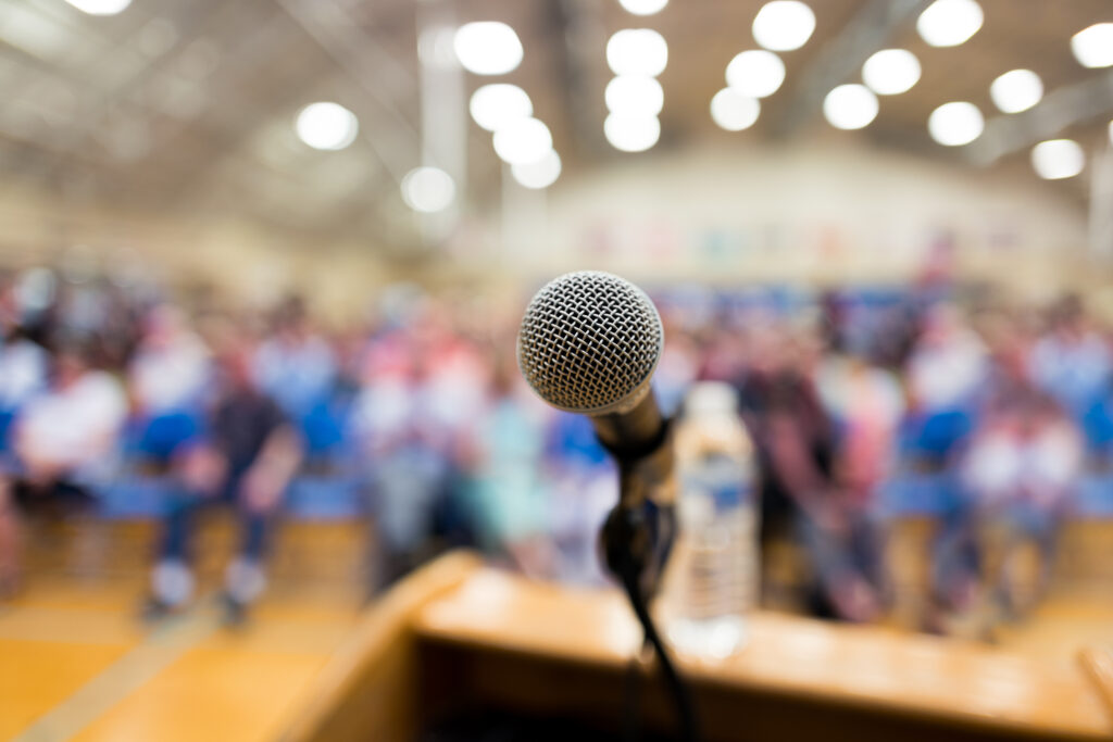 a microphone at a podium, the background a blurred audience