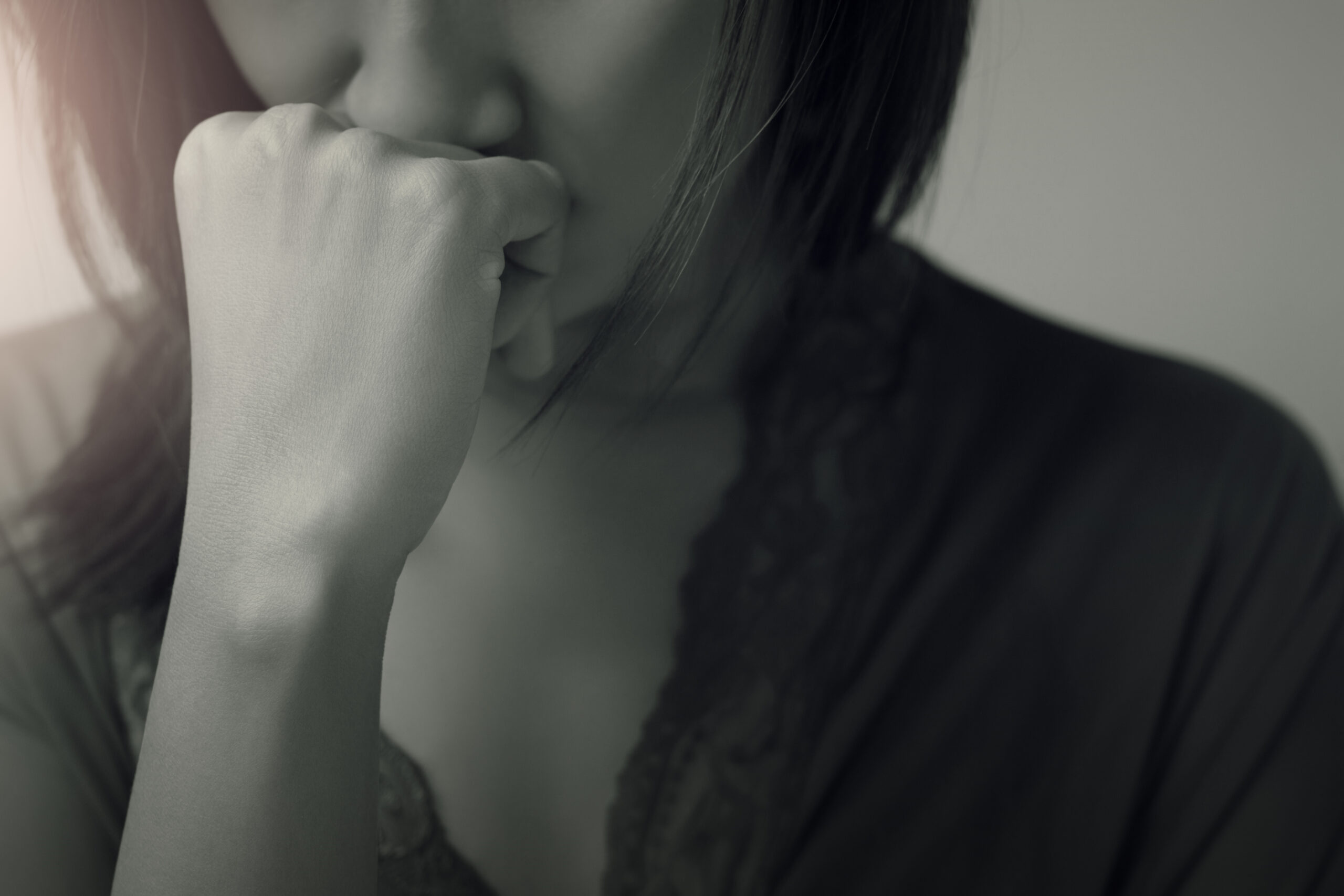 a woman holds her fist to her face in a pensive manner