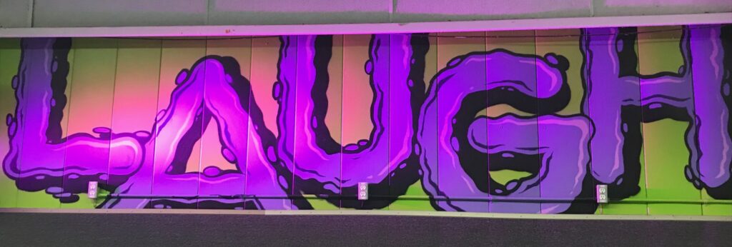 LAUGH written in purple bubble letters on a green painted wall of the Auburn Skate Connection