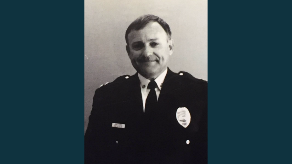 A black and white photo of man in a dress police uniform.
