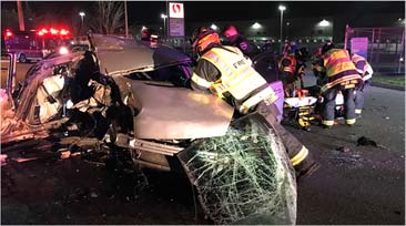 Firefighters work to remove a patient from a crumbled vehicle after a collision.