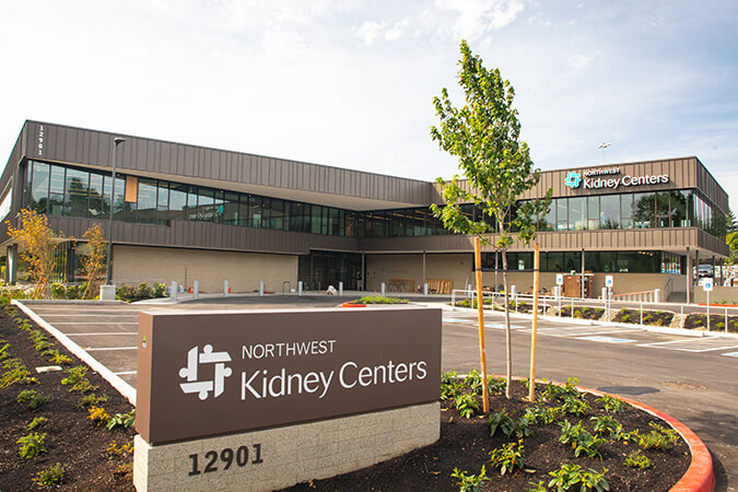 A brown and glass office building with a sign in the foreground that reads "Northwest Kidney Centers"