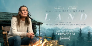 Robin Wright sits by a fire with a log cabin behind her in a mountain top setting on the movie poster for LAND