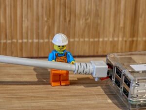 A lego construction man plugs in a broadband cable to a router