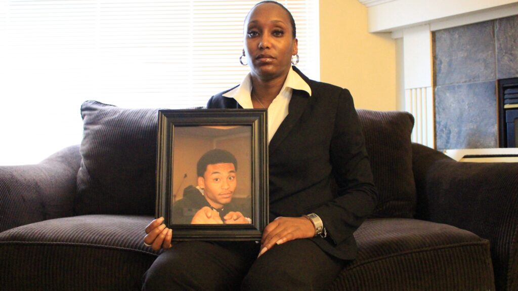 Shalisa Hayes, an African American woman, sits on a couch holding a large photo of her son, Billy Ray