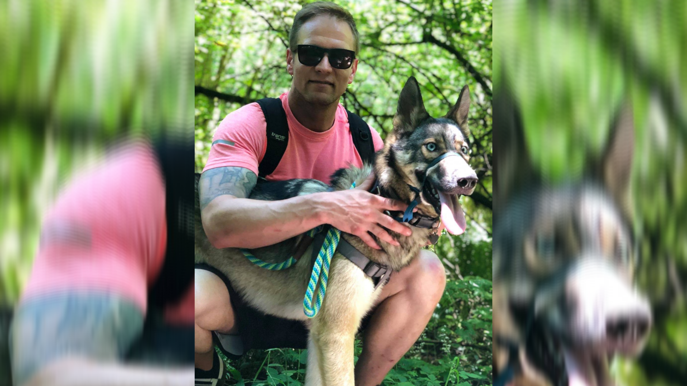 Joey, an white adult male, and Max, a German Shepherd mix dog, together. Joey is crouch down next to Max outside in a wooded area on a sunny day.