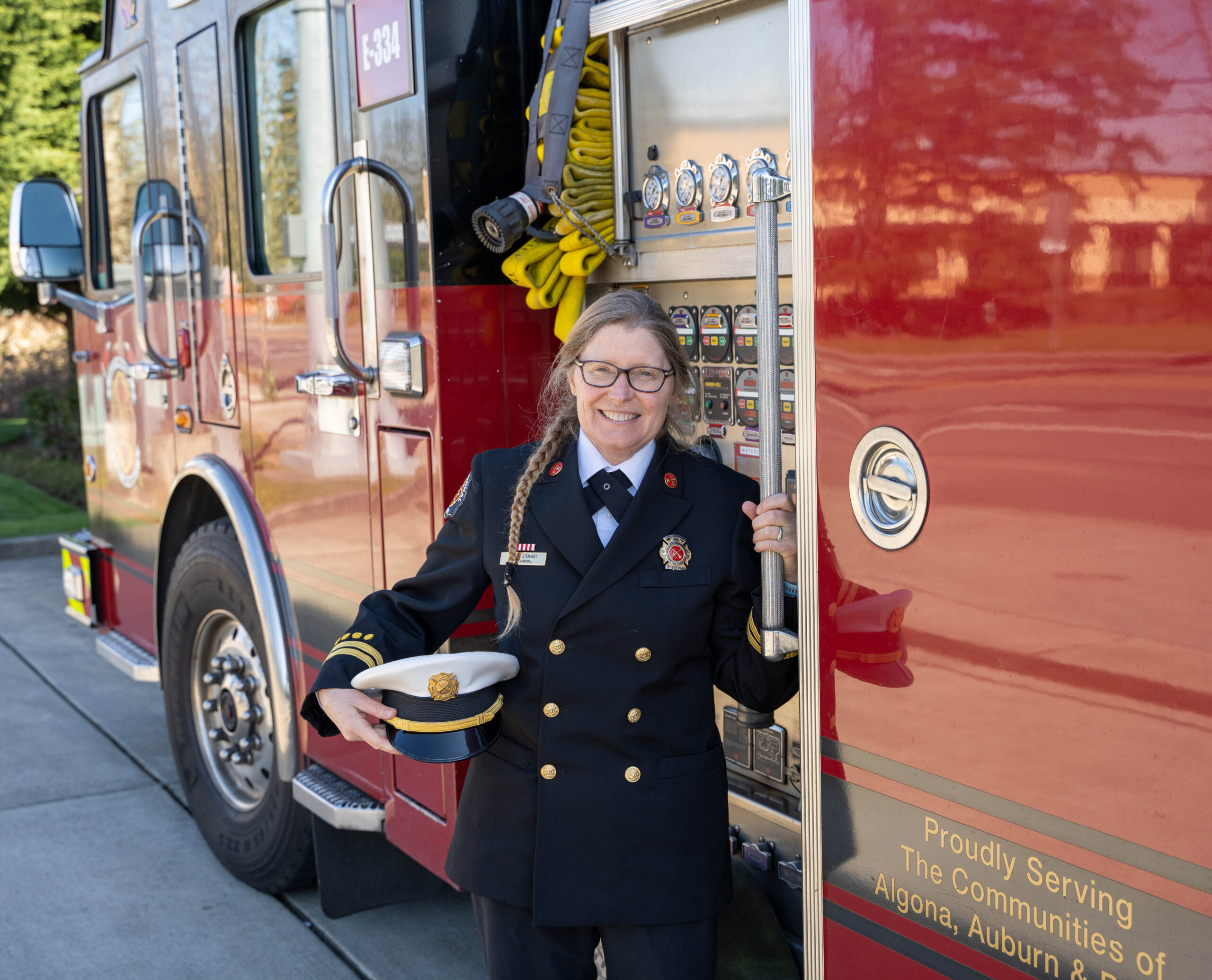 Fire Marshal Karen Stewart stands next to a fire truck in her dress uniform.