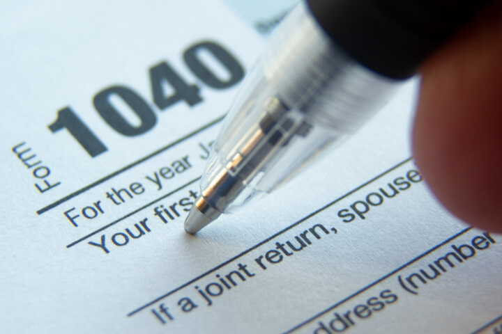 A pen is poised to begin filling out a 1040 tax form