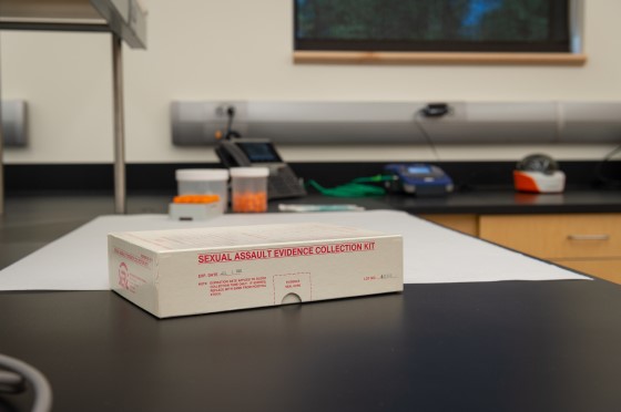 A white box with "Sexual Assault Kit" on the side sits on a black top lab table