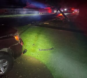 A damaged Honda Pilot sits in the front yard of a home, damage from a collison in its wake.