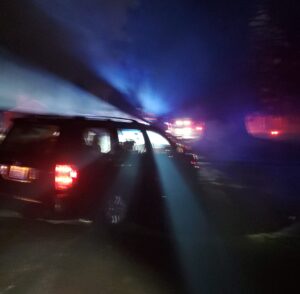 Police Lights shine through an abandoned vehicle from a single car collison that sits in the yard of an uninvolved home