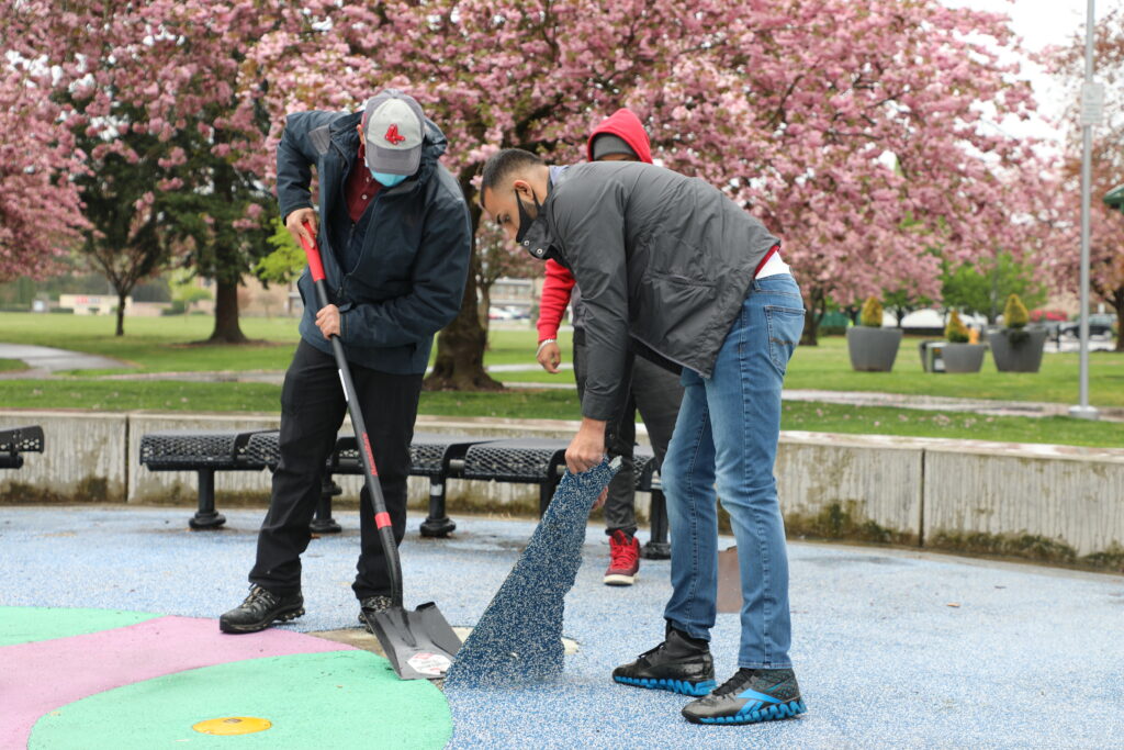 volunteers work to remove coating on the Les Gove splash pad during Auburn's Clean Sweep 2021