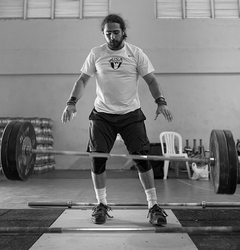 A black and white photo of Harrison Maurus, a large barbell falling to the ground in front of him.