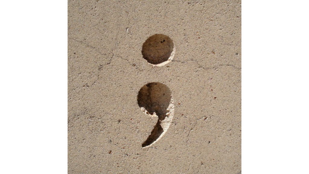 a semicolon etched in tan stone