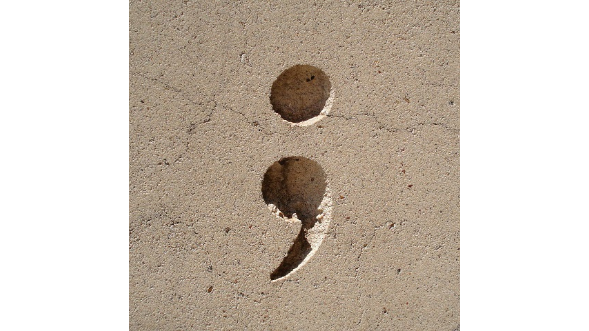 a semicolon etched in tan stone
