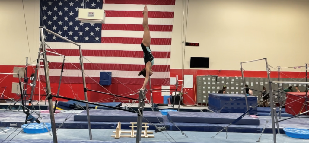 Jocelyn Sasson practices on the uneven bars at Ascend Gymnastics in Auburn, the photo captures here vertical on the high bar.