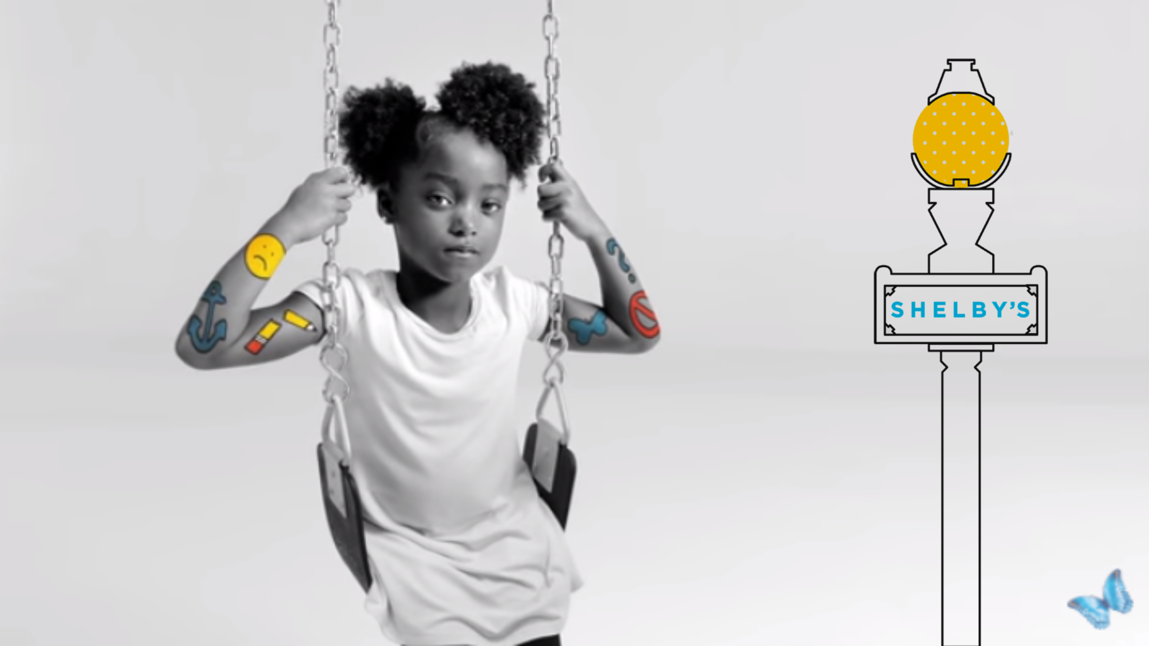 A little girl sits on a swing, holding its chains. Her arms have colorful icons symbolizing her emotions. A light pole with "Shelby's" is to her right.