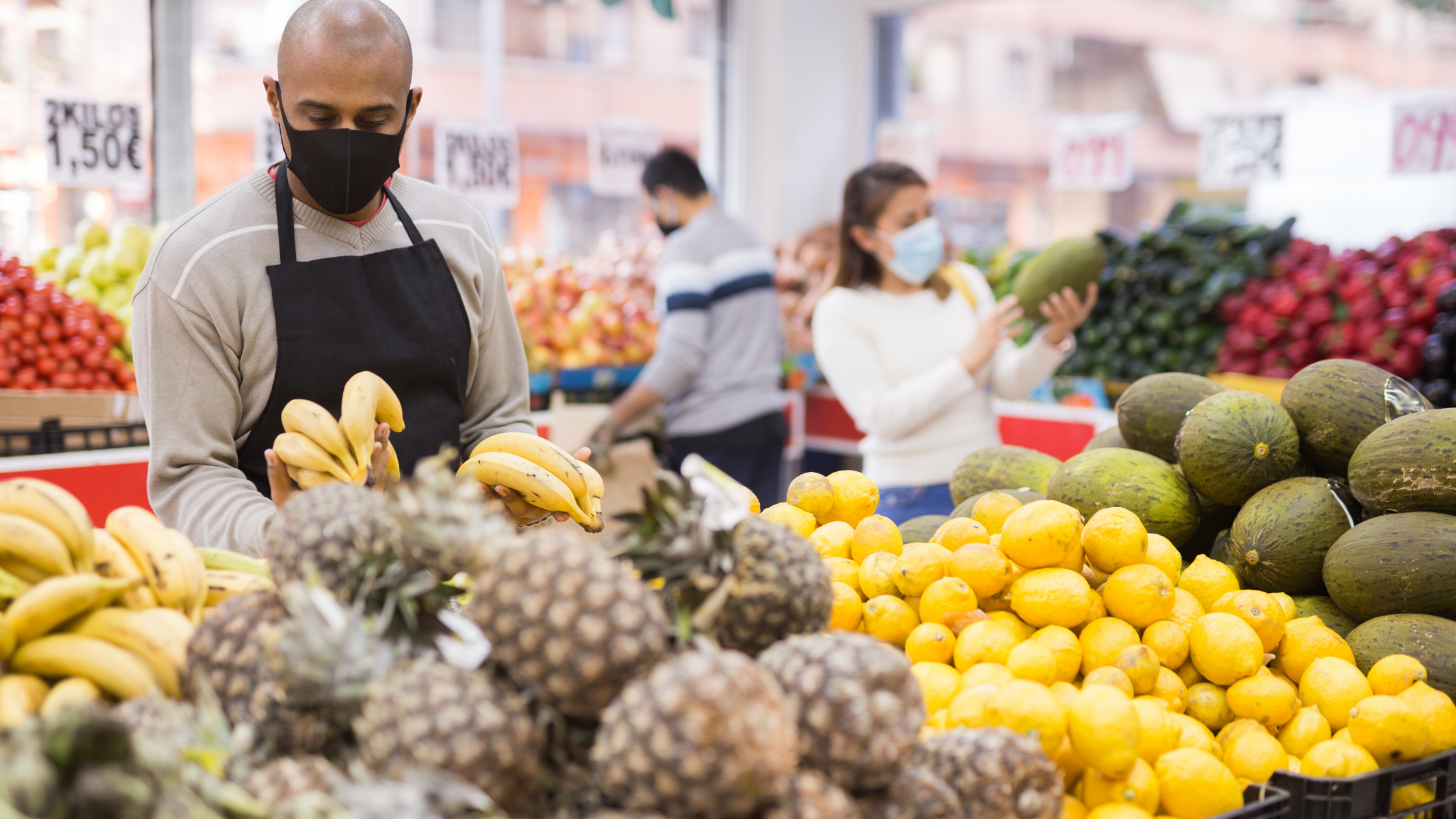a male grocery store worker wears a cloth mask as he restocks produce