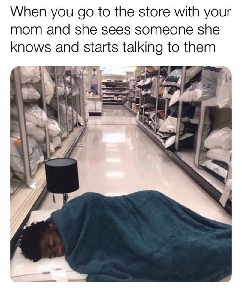 a mem of a guy laying down with a pillow and blanket in a store.