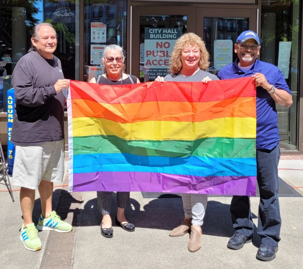 Auburn Mayor Nancy Backus and City Councilmembers Chris Stearns, James Jeyaraj, and Yolanda Trout hold a pride flag together