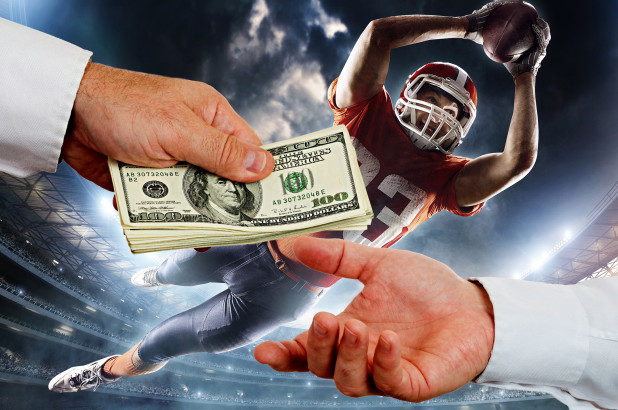 a football player jumps to catch a ball, in front of him two people exchange a stack of money.