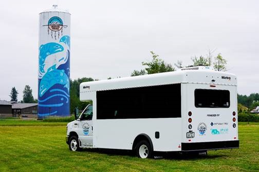 An electric bus in front of a Muckleshoot water tower.
