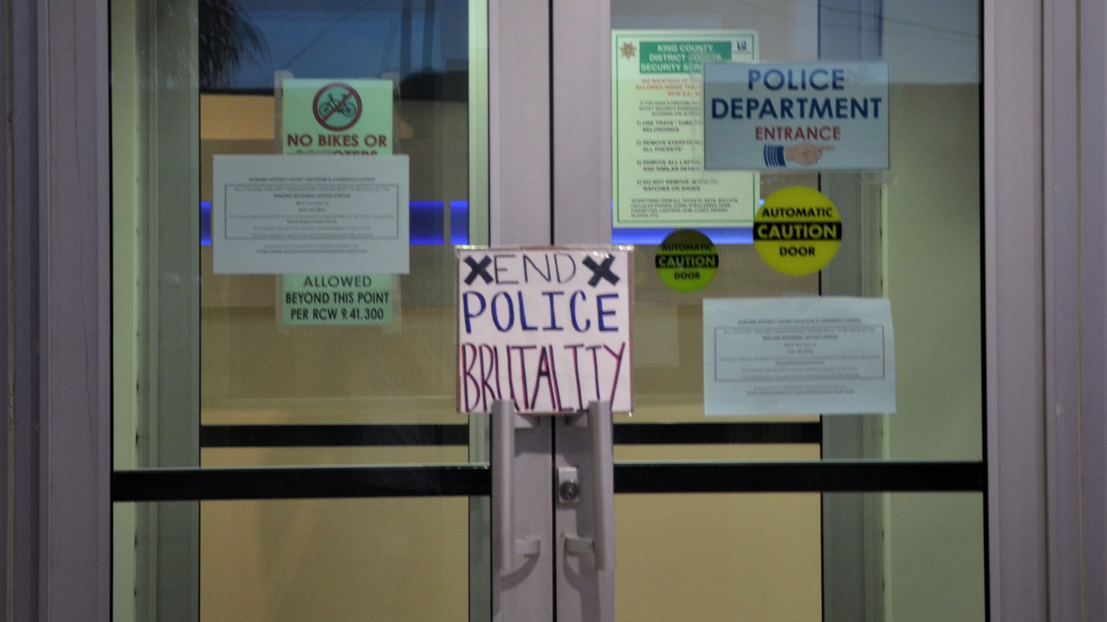 A sign reading "End Police Brutality" sits on the doors to the Auburn Justice Center