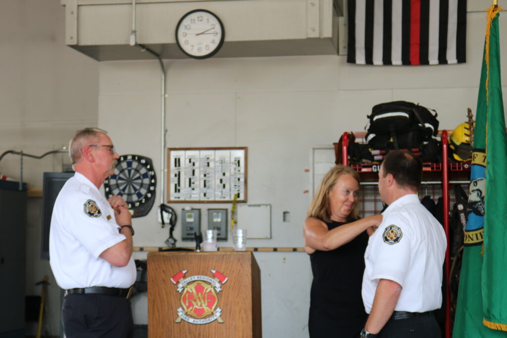 VRFA Chief Brad Thompson receives his Chief's pin, placed on his lapel by his wife. Retired Chief Brent Swearingen stands across from Thompson having just removed the pin from his lapel.