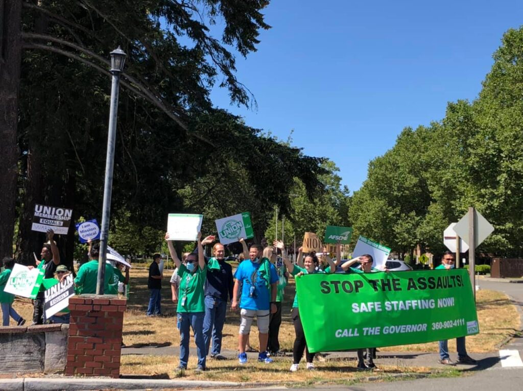 A group of healthcare workers hold up signs during a protest