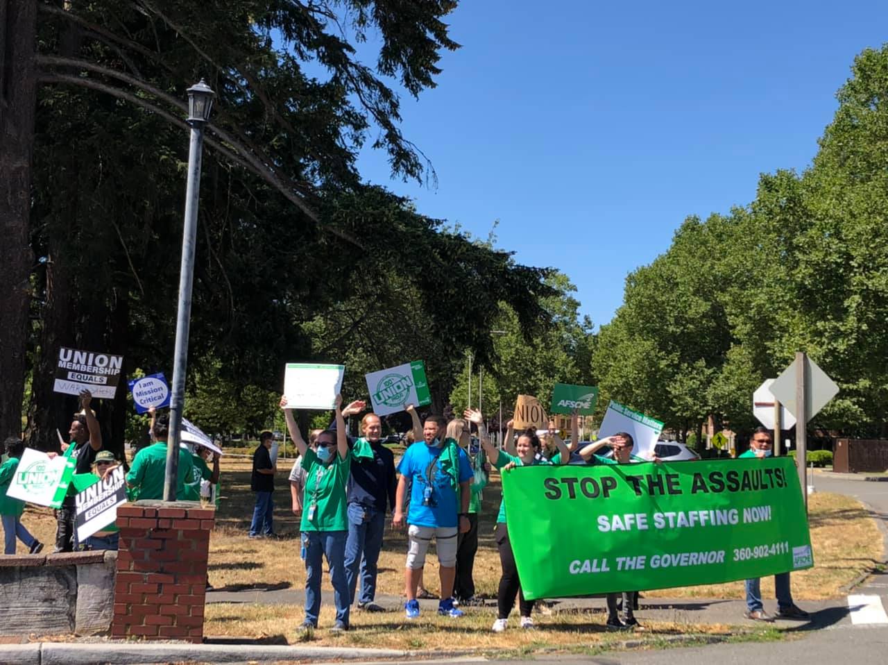 A group of healthcare workers hold up signs during a protest