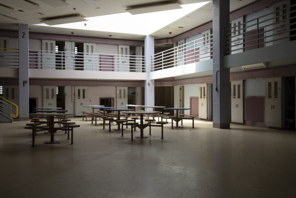 Empty interior of cell block in Correctional Institution, or jail., common room with jail cells.