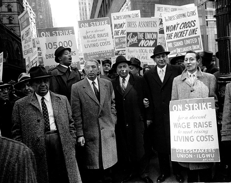A group of dressmakers on strike hold signs urging unionization and fair labor practices