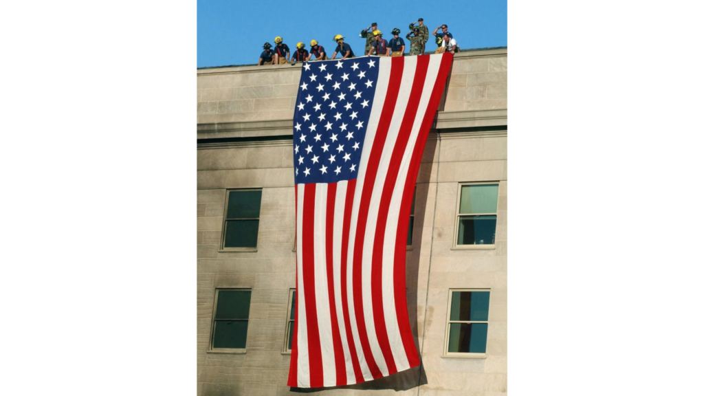 First responders and military personnel drape an american flag over the side of the Pentagon