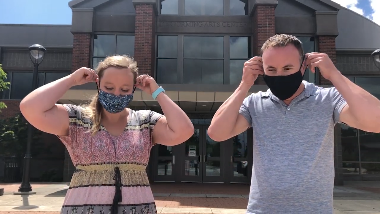 A male and female pull on two facemasks