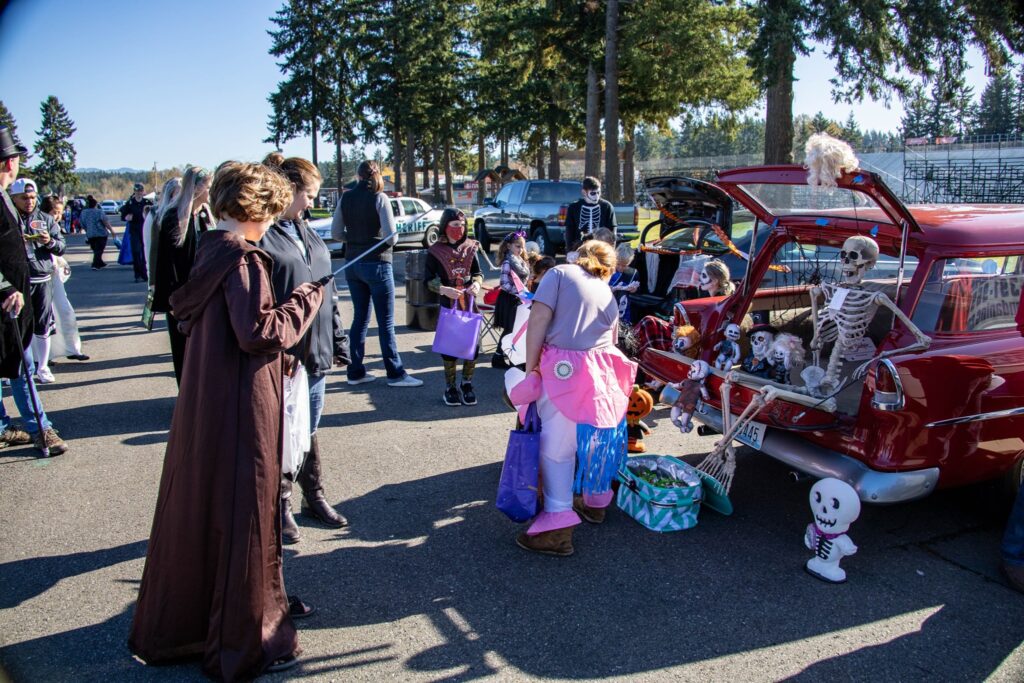 Families gather around decorated cars during a trunk or treat event