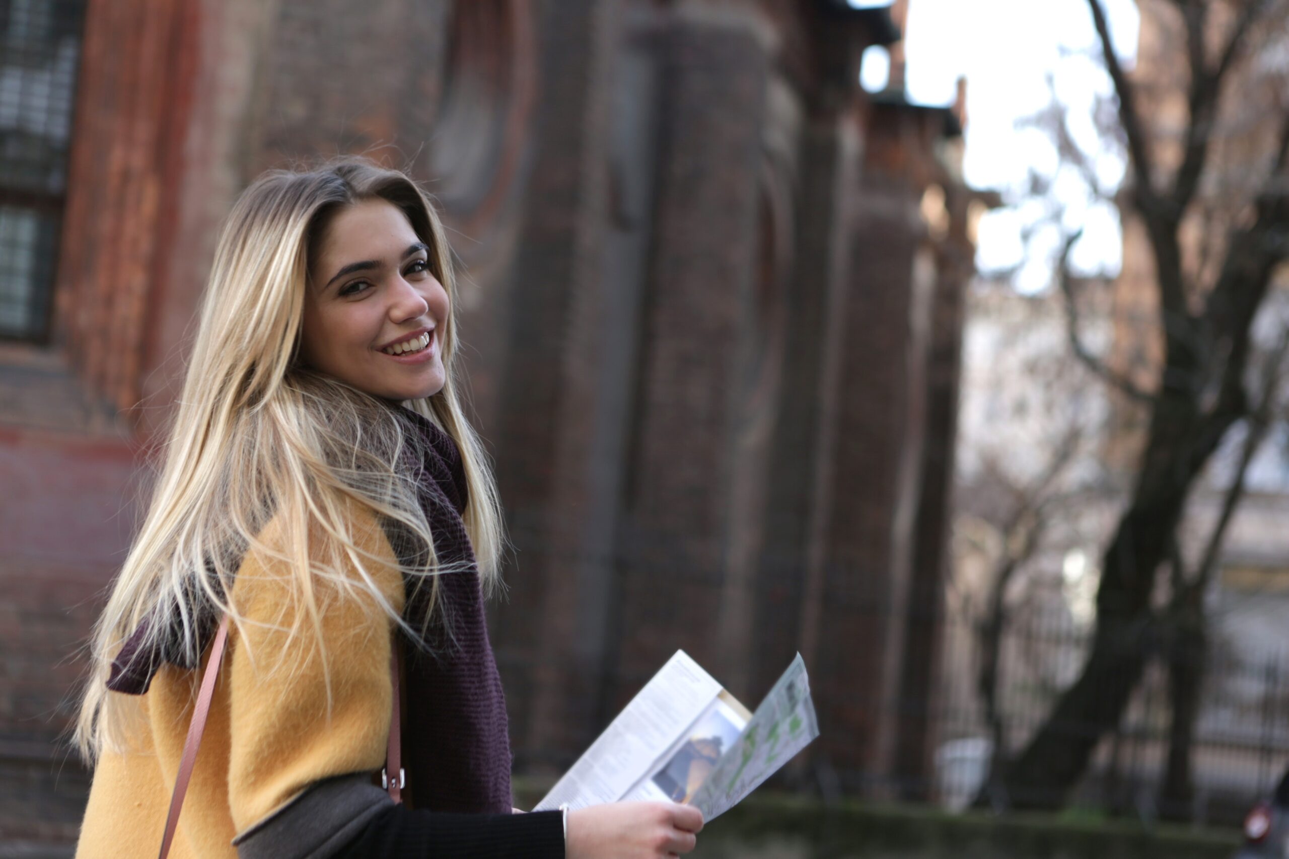 A blonde female holds a map while touring a college campus