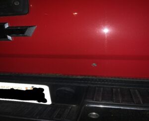 a red Chevrolet tailgate with a bullet hole in it