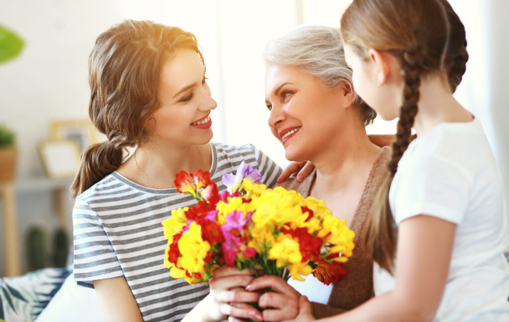 three generations of a loving family mother, grandmother and daughter holding a bouquet of colorful flowers