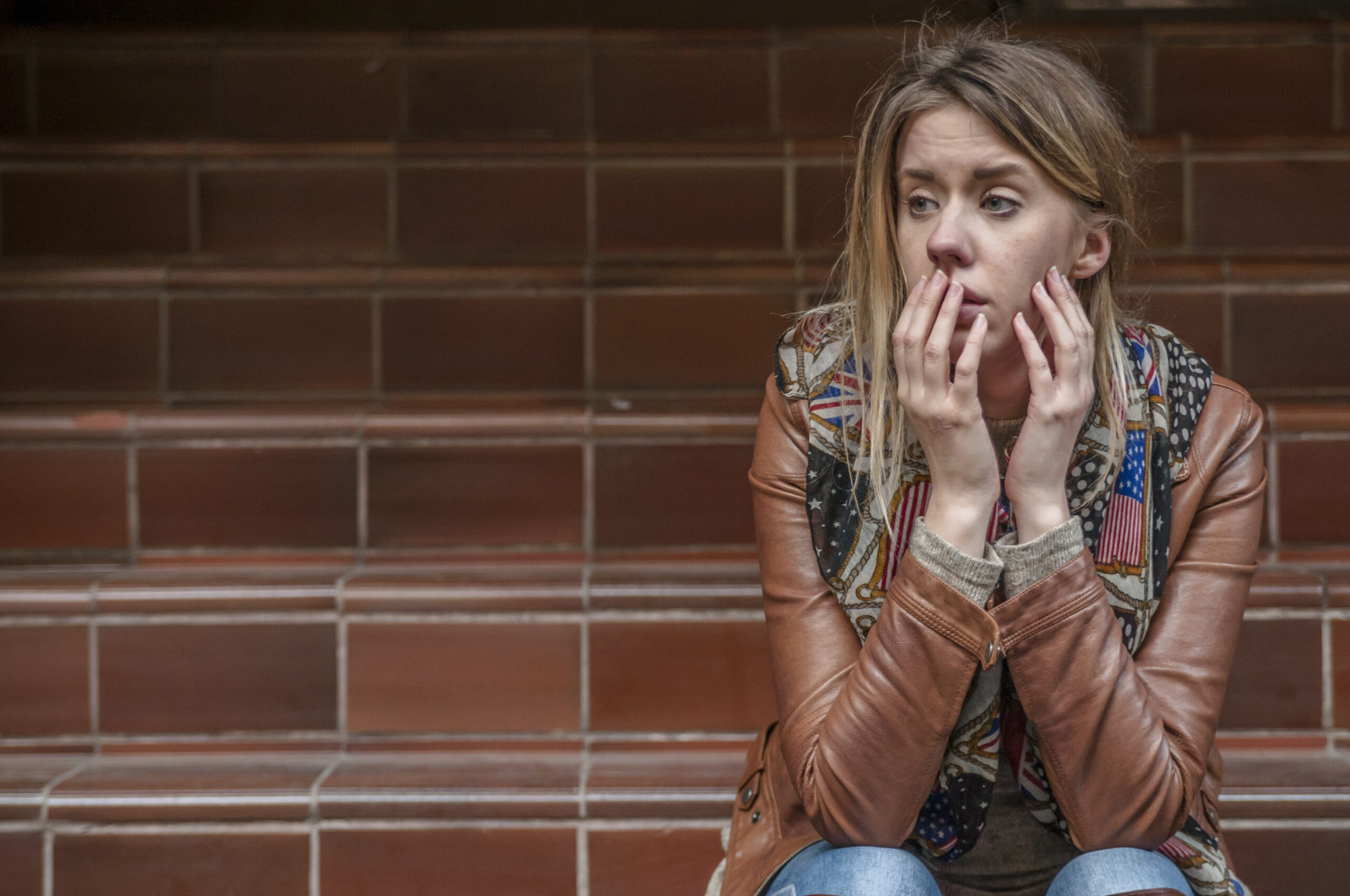 Teenage girl thinking. Young woman frustrated on the stairs. Sad girl. Girl thinking and sitting on steps, holding her head