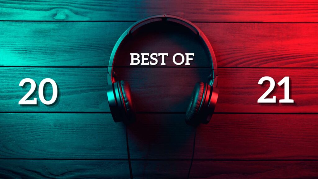 A pair of headphones lay on a wood table, teal and red lights shining on either side. Best of 2021 is written over the headphone