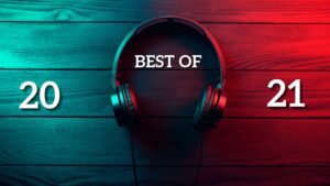 A pair of headphones lay on a wood table, teal and red lights shining on either side. Best of 2021 is written over the headphone