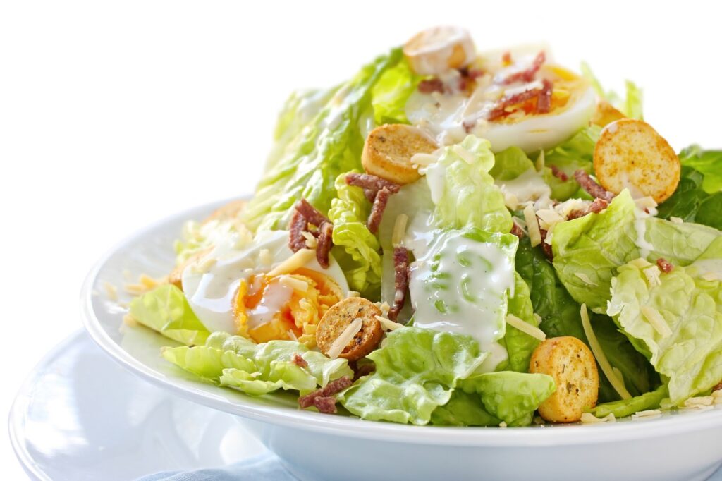 a leafy green salad with crotons and ranch dressing
