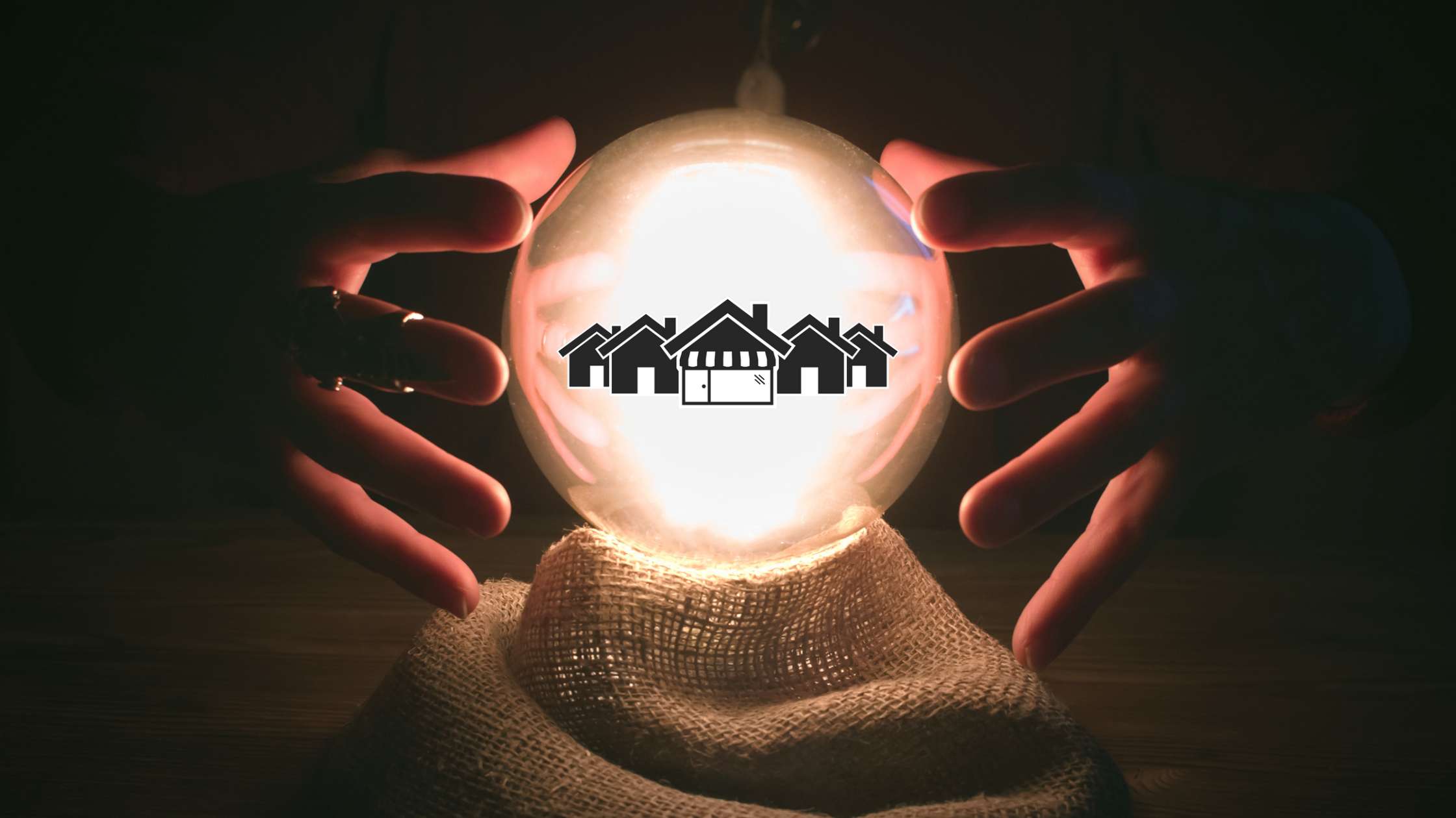 A hair of hands hover over a glowing crystal ball. Inside the crystal ball are 5 black houses