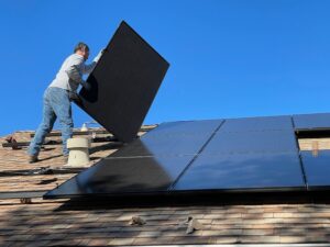 A worker installs solar panels on the roof of a house