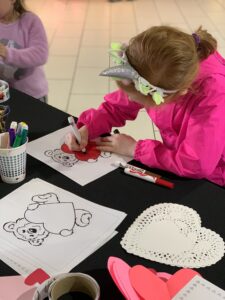 A young girl colors a teddy bear picture