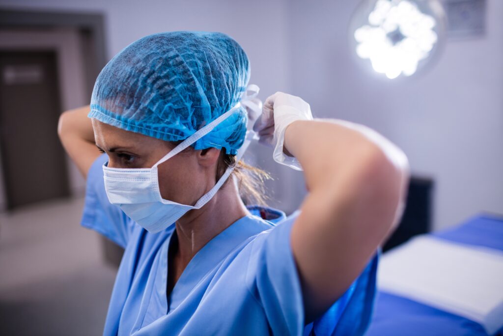 Female nurse tying surgical mask in operation theater