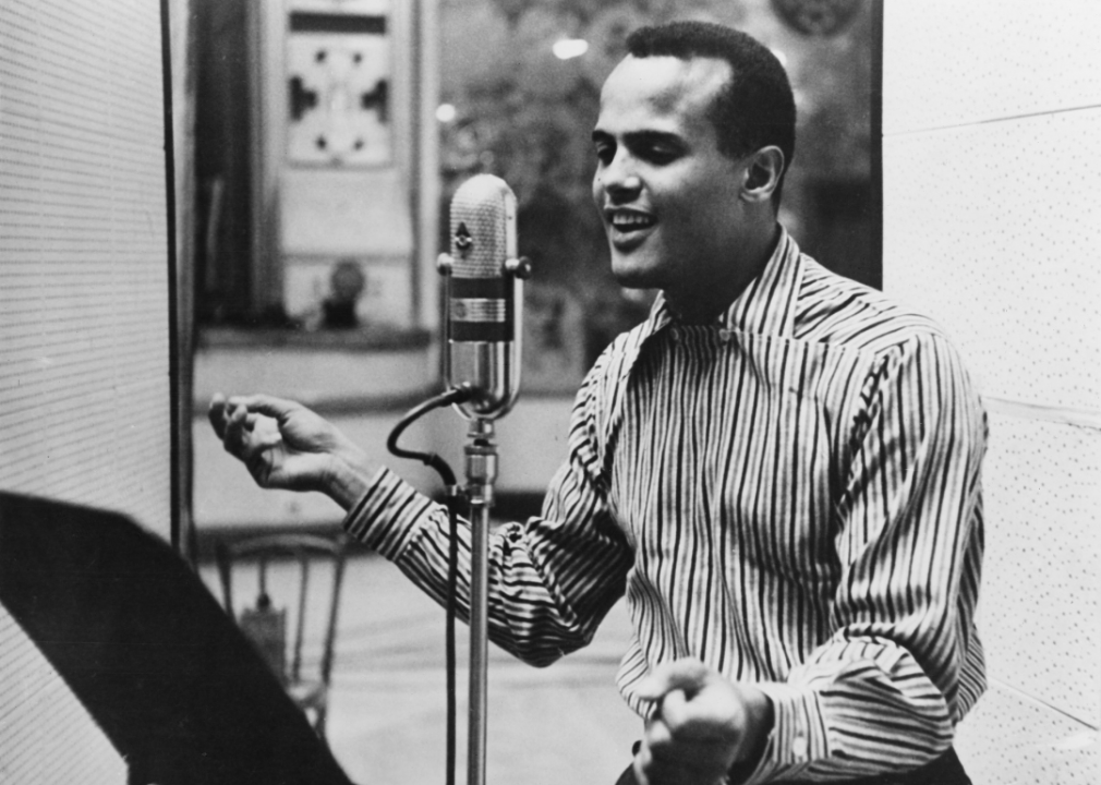 Famous Black actor Harry Belafonte stands before a microphone in a studio
