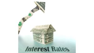 a house made of dollar bills sits under a jagged arrow, also made of money, rising above it