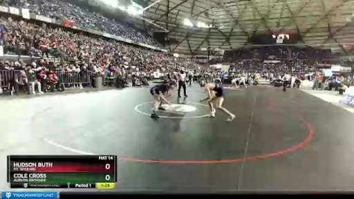 Two male students wrestling on a large black mat